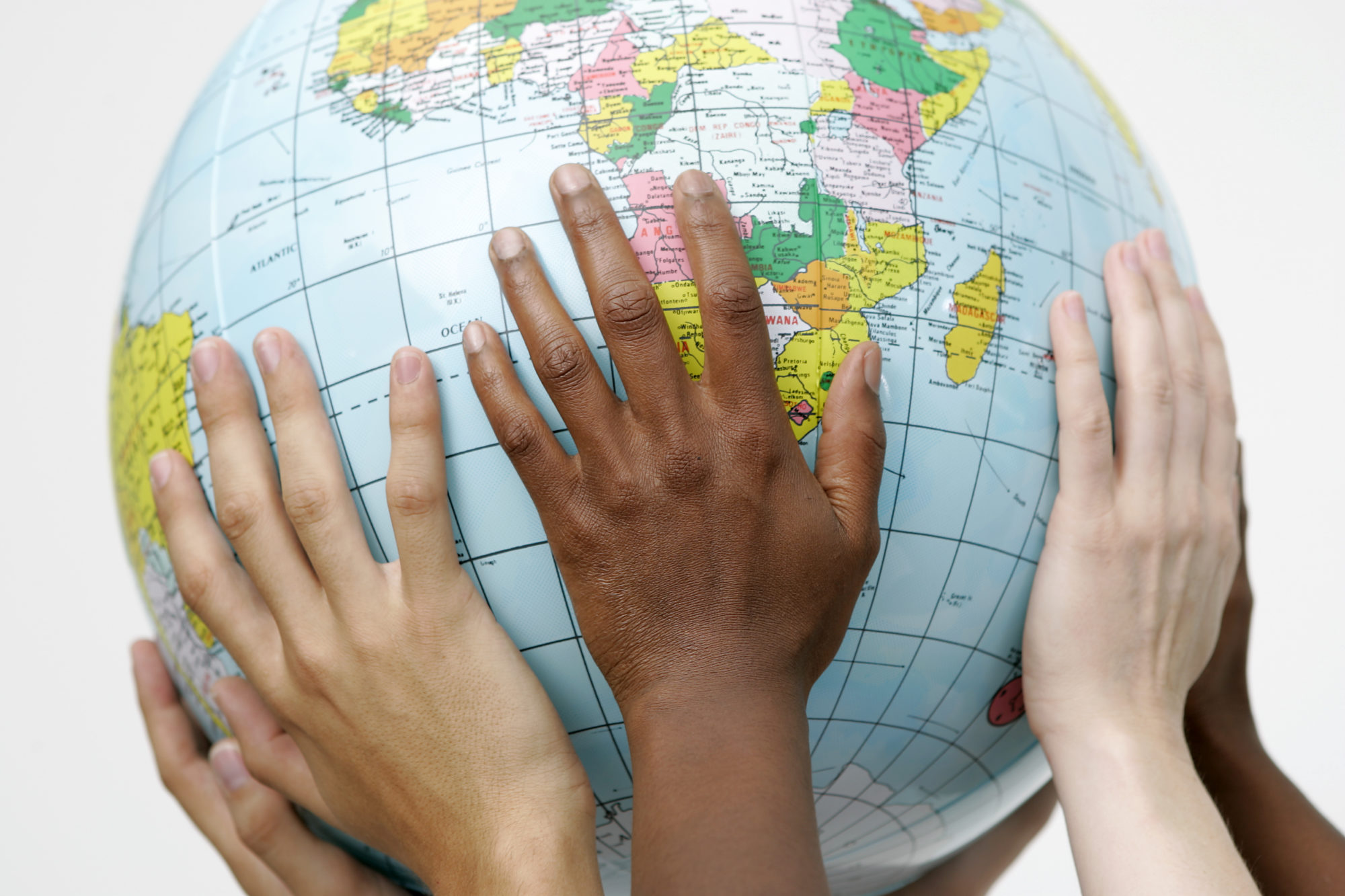 Hands of different skin tones reaching across a globe