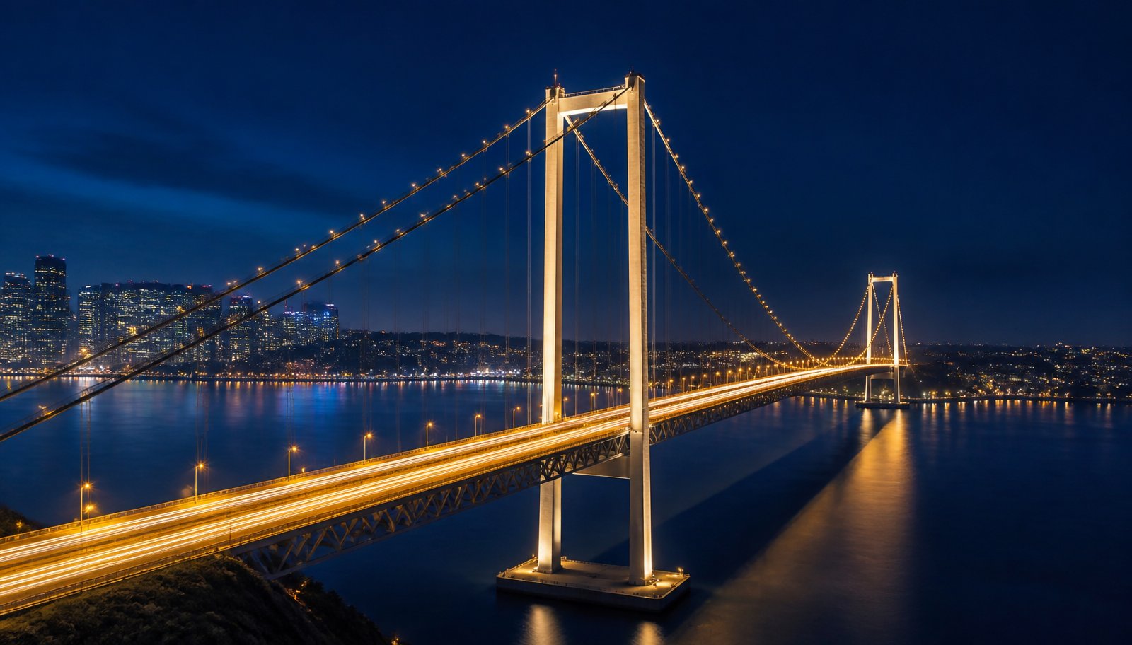 Illuminated bridge over water connecting a city skyline at dusk